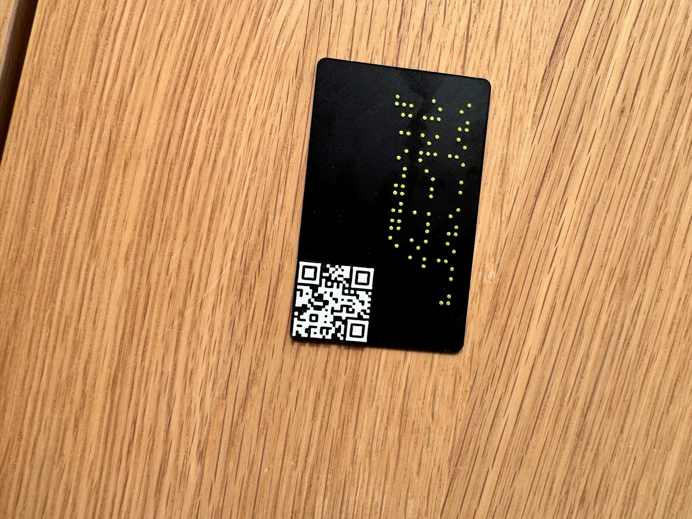A 3D-printed Braille business card is shown from the front, with raised Braille text and a raised QR code.