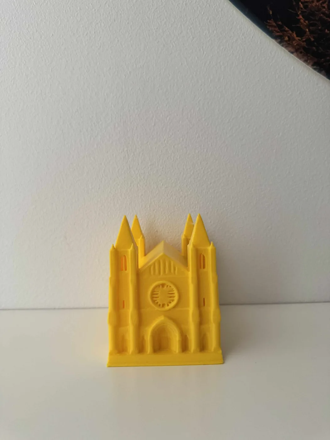 A front view shows a golden-yellow 3D-printed Braille Cathedral with twin spired towers, a round rose window, lancet windows and a deep arched doorway.