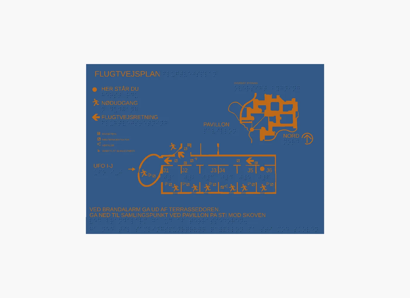 A flat top view shows a tactile emergency evacuation plan on a blue plate, with raised orange graphics, Braille labels, tactile routes, room labels, exit symbols, a north arrow and Danish instruction text.